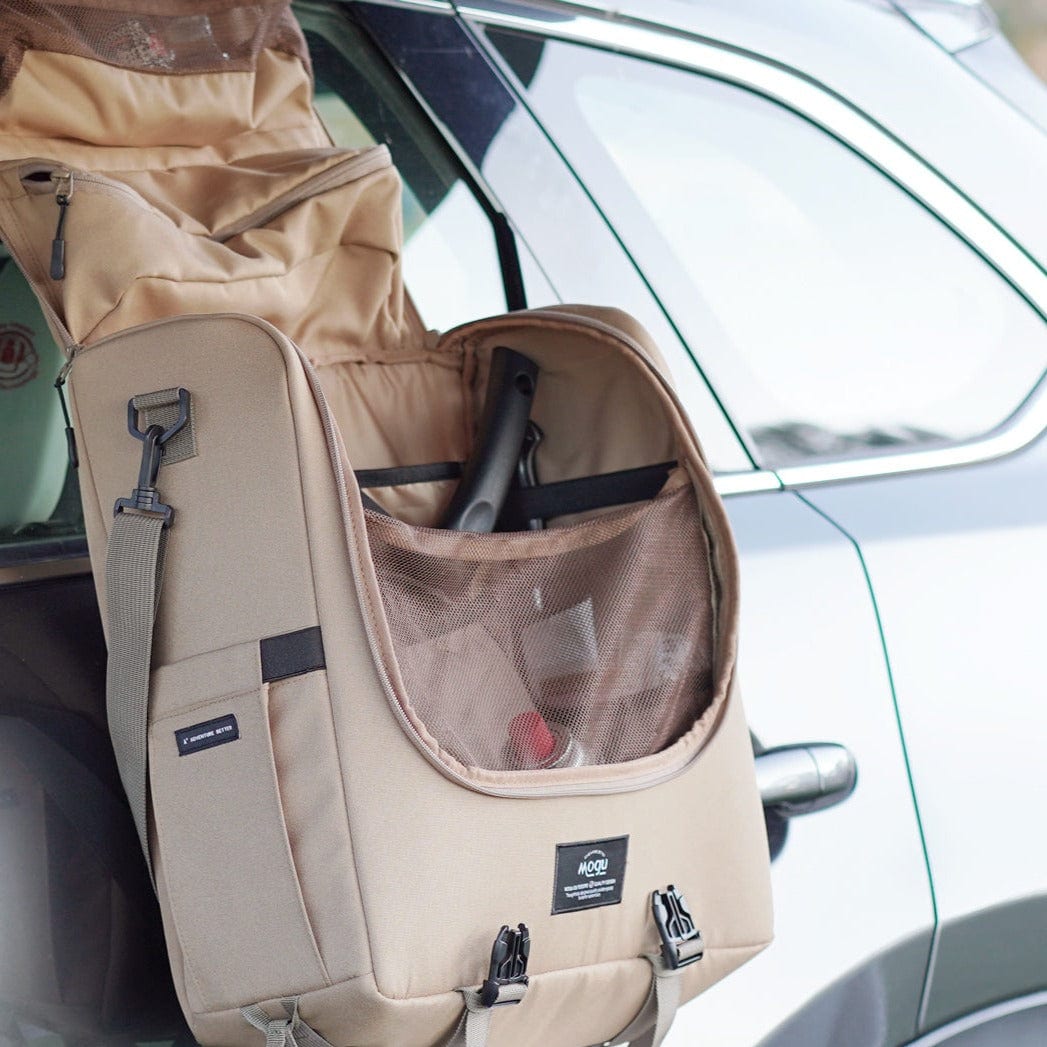 Camp kitchen caddy hanging on side of car, open with a wide compartment for cooking gear and pouches for utensils and herbs.